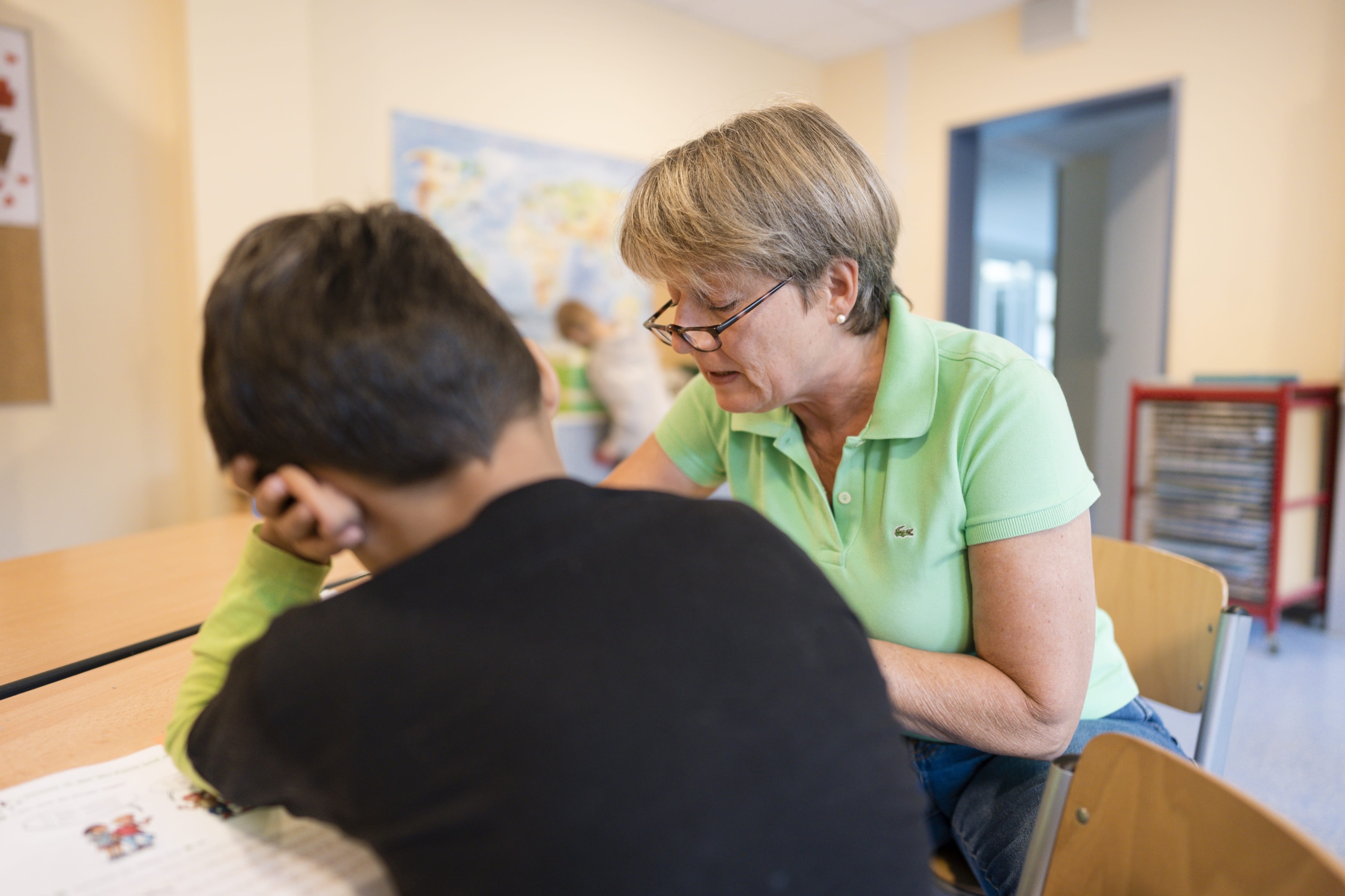 Lehrerin und Schüler sitzen am Tisch und lernen.